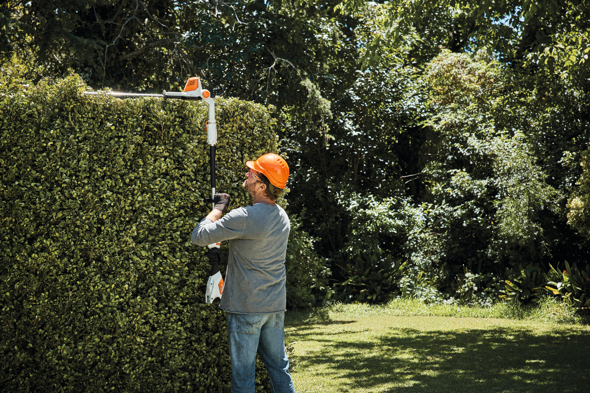 Mies leikkaa pensasaitaa HLA 56 -pensasleikkurilla